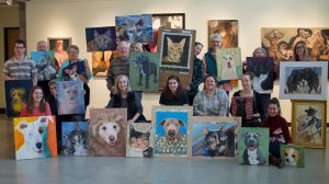 Students show off their paintings of local shelter cats and dogs that will be sold for a fundraiser for Clatsop Animal Assistance