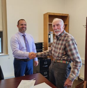 Board of Education Chair Ed Johnson shakes hands with Jarrod Hogue after signing the contract papers making Hogue the new president of CCC.